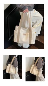 Dettaglio della borsa tote in tela crema con tasca laterale ed etichetta del marchio