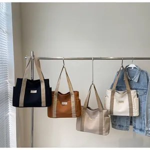 Borse tote minimaliste in tela in quattro colori esposte su un supporto con tasche
