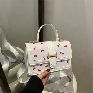 White cherry print crossbody bag with gold buckle and wide shoulder strap