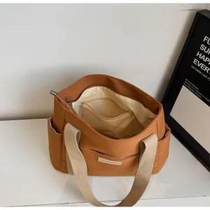 Vista dettagliata della borsa tote in tela marrone con fodera interna e cerniera in metallo