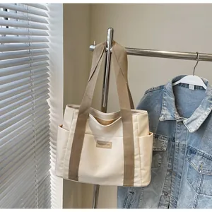 Dettaglio della grande borsa tote in tela con tasche laterali e un'etichetta in pelle