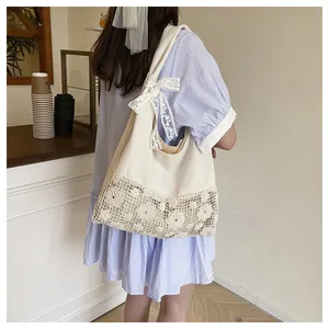 Close-up of beige canvas tote bag featuring delicate lace flower embroidery and a bow strap