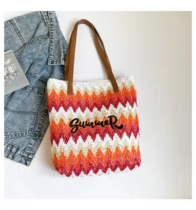 Detail of wave striped straw tote bag featuring Summer embroidery and leather handles