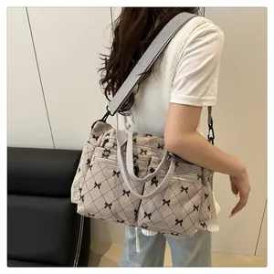Detail of a beige tote bag with bow print and multiple zip pockets shown in a lifestyle scene