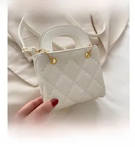 Macro shot of the quilted white leather texture and golden metal hardware on this mini handbag
