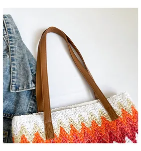Detail of colorful zigzag straw tote bag with brown leather handles and soft lining