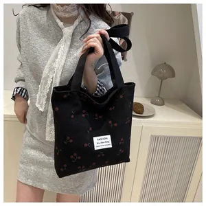 Dettaglio della borsa tote in velluto nero con stampa a ciliegie ed etichetta tessuta