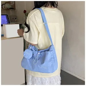 Close-up of light blue nylon tote bag showing pleated texture and small coin purse charm