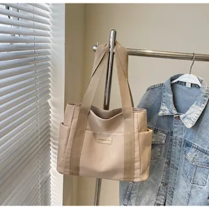 Dettaglio della grande borsa tote in tela con tasche anteriori ed etichetta Fashion & Bags