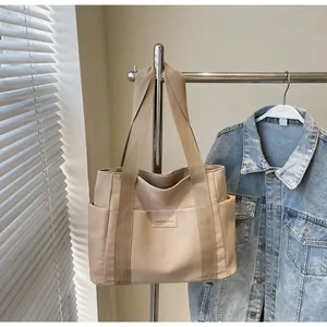 Dettaglio della borsa tote in tela beige con tasche laterali ed etichetta moda