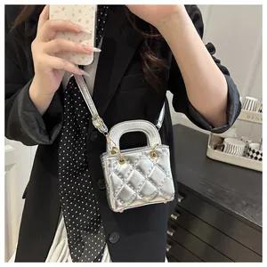 Selfie miroir montrant un mini sac matelassé argenté avec des détails dorés et bandoulière