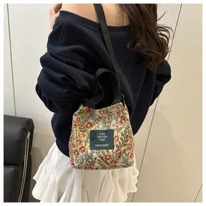 Détail d'un sac bandoulière brodé de fleurs avec motifs jacquard colorés et étiquette verte