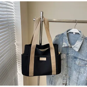 Dettaglio della borsa tote grande in tela con tasche laterali e manici beige