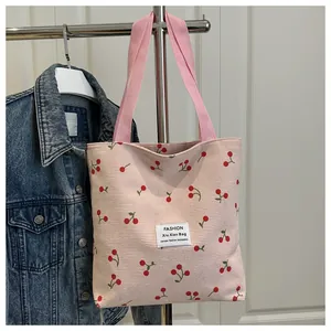 Dettaglio della borsa tote in velluto a coste rosa con stampe di ciliegie e manici in tessuto