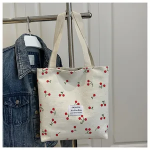 Dettaglio della borsa tote in tela crema con stampa a ciliegie rosse e trama intrecciata