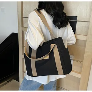 Vista dettagliata della borsa tote in tela nera con manici beige portata a spalla