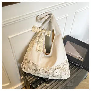 Detail of canvas tote bag featuring floral lace trim and elegant bow on suitcase