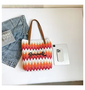 Detail of hand-woven straw beach bag with red wave pattern and Summer embroidery