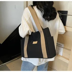 Dettaglio del retro di una borsa tote in tela nera con spalline beige su una modella