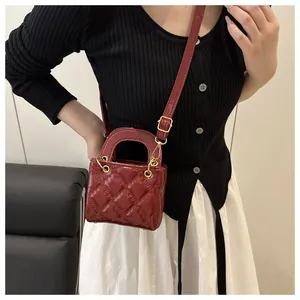 Gros plan du sac à main en cuir verni matelassé bordeaux avec détails dorés chic