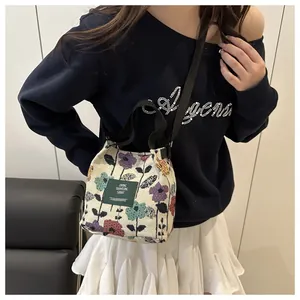 Détail de broderie florale vintage sur un petit sac seau couleur blanc cassé