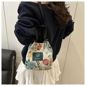 Détail de la broderie florale sur sac seau ethnique vintage avec bandoulière tissée