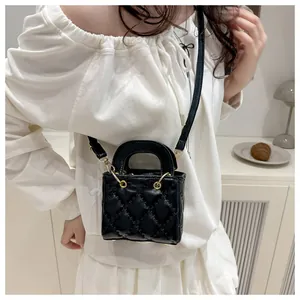 Détail du sac à main en cuir matelassé noir avec finitions dorées et poignée ronde
