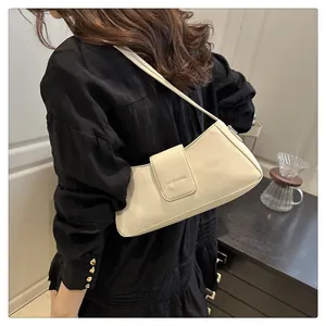 Detailed view of cream patent leather underarm bag with minimalist brand logo lettering