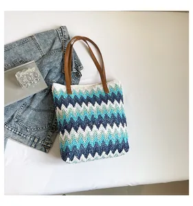 Detail of colorful zigzag wave patterns on a woven straw tote bag with brown leather handles