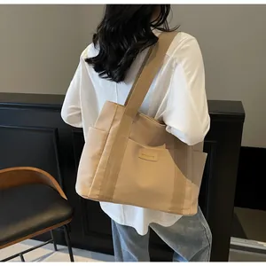 Dettagli borsa tote in tela beige con tracolla ampia ed etichetta decorativa in pelle