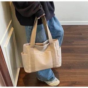 Dettaglio della borsa tote in tela beige con tasca laterale e trama del tessuto di qualità