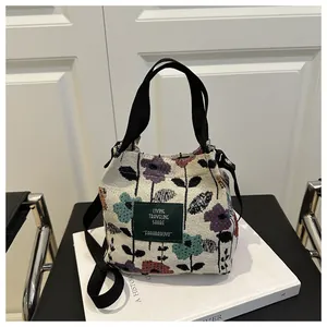 Gros plan sur un sac seau ethnique avec broderies florales et détail d'étiquette en cuir