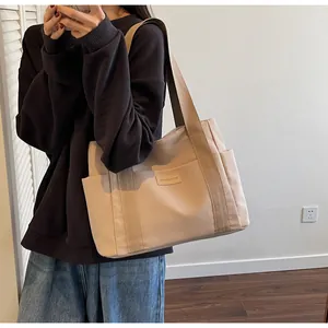 Dettaglio della borsa tote in tela beige con tracolle marroni e tasca frontale con etichetta
