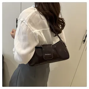 Close-up of dark brown patent leather underarm bag with silver embossed lettering