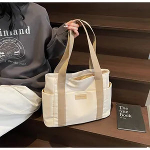 Dettaglio della borsa tote in tela crema con tasche laterali ed etichetta in pelle