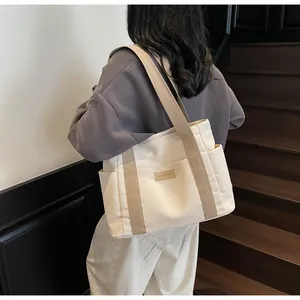 Donna indossa borsa tote in tela con tasche laterali ed etichetta moda su scale