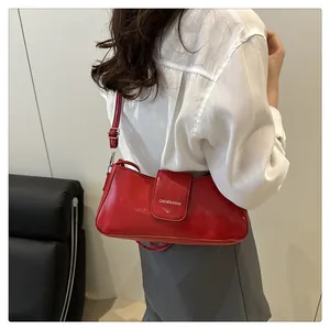 Detailed view of red patent leather shoulder bag with glossy finish and logo