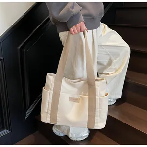 Dettaglio della borsa tote in tela crema con manici marroni e toppa 'FASHION & BAGS' cucita