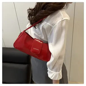 Close-up of stylish red glossy patent leather underarm bag with silver brand logo