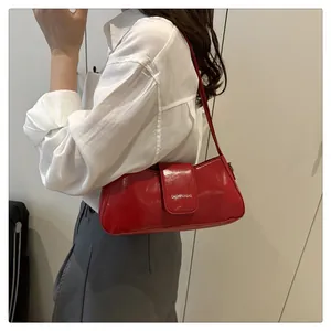 Side view of a glossy red patent leather underarm bag worn on the shoulder over white shirt