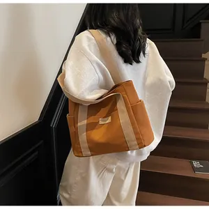 Dettaglio della borsa tote in tela caramello con tasca laterale e etichetta alla moda