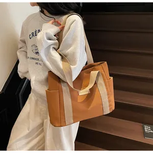 Borsa tote in tela marrone con tasche laterali indossata da modella sulle scale