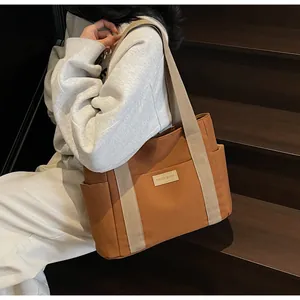 Borsa tote in tela marrone con tracolle bianco sporco ed etichetta su scale di legno
