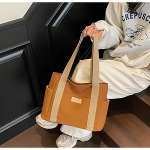 Dettaglio della capiente borsa tote in tessuto marrone con tracolla a contrasto