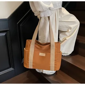 Dettaglio della borsa tote in tela caramello con cinturini in tessuto beige e tasca laterale