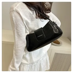 Close-up of black patent leather underarm bag with sleek glossy finish and white logo detail