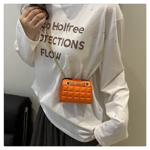 Detail van levendige oranje gewatteerde minitas met gouden ketting en zachte textuur