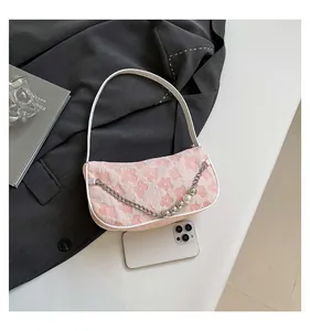 Detailed view of pink floral jacquard fabric with elegant pearl chain on a shoulder bag
