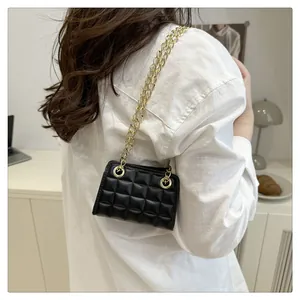 Detail of black quilted mini chain bag worn by model in a minimalist lifestyle setting