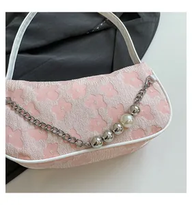 Macro detail of pink floral jacquard fabric with elegant pearl and silver metal chain